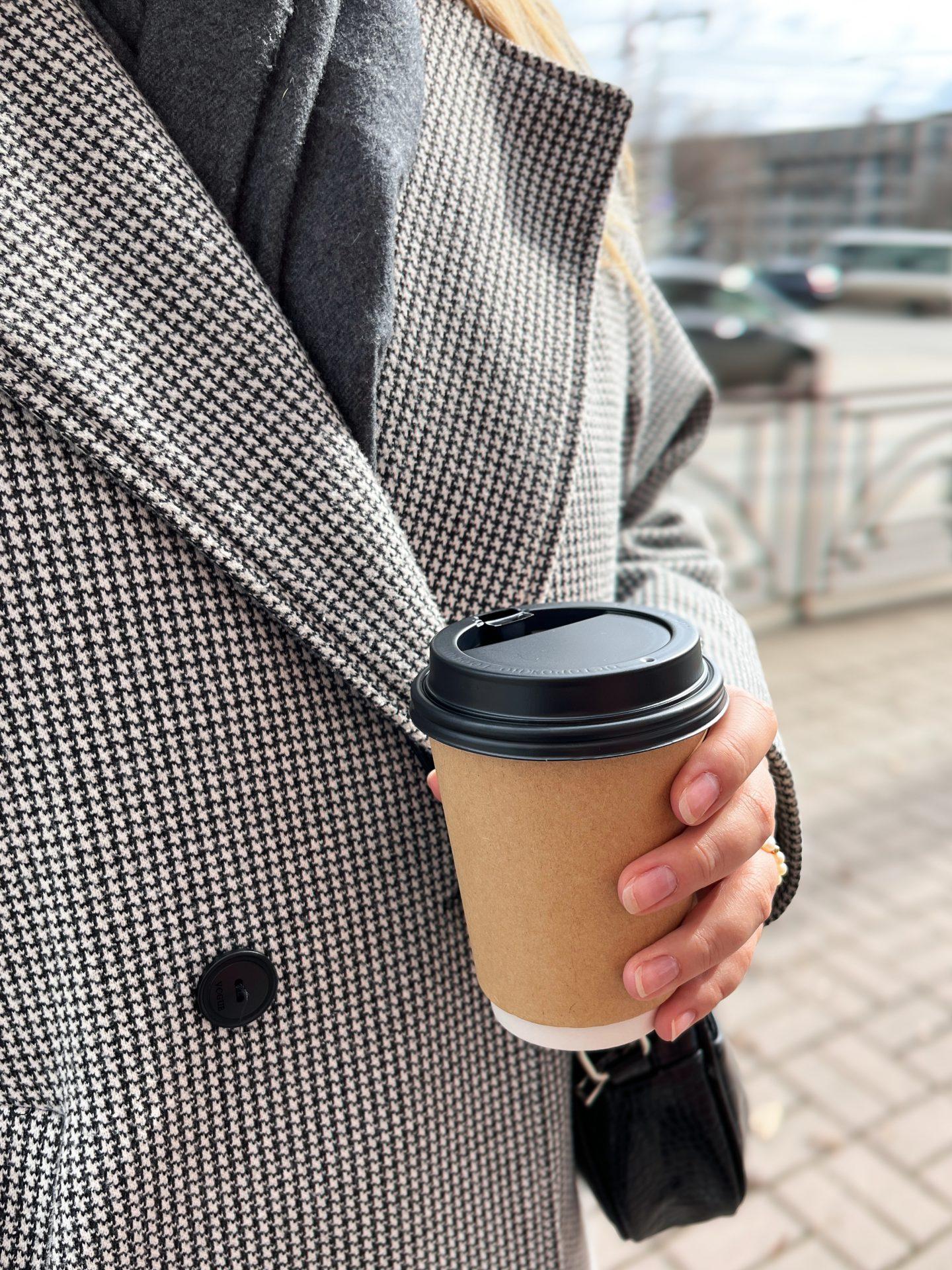 dłoń kobiety trzymająca kubek ekologiczny z kawą