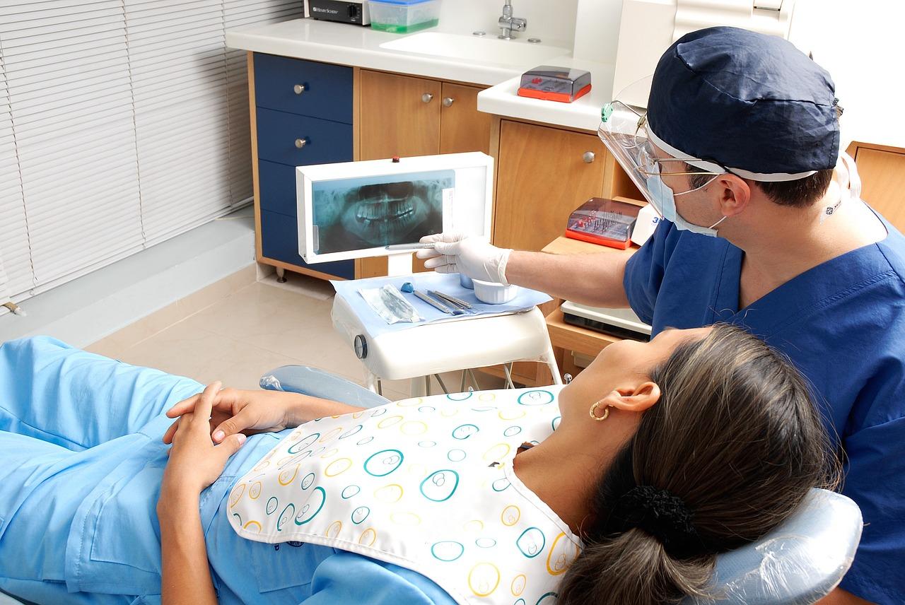 dentysta z pacjentem na fotelu pokazuje zdjęcie rentgenowskie
