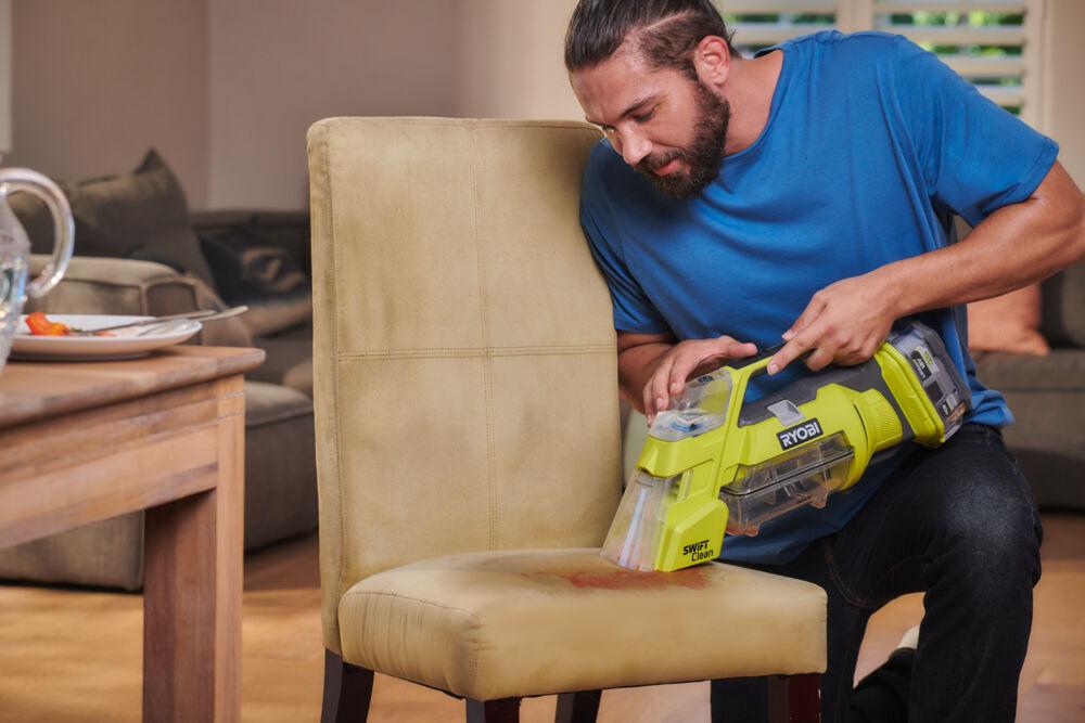 Mężczyzna używa RYOBI SWIFT CLEAN do czyszczenia tapicerki na krześle