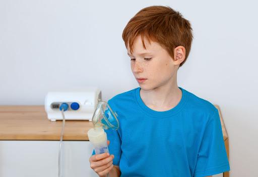 chłopiec trzymający w dłoni maseczkę inhalatora