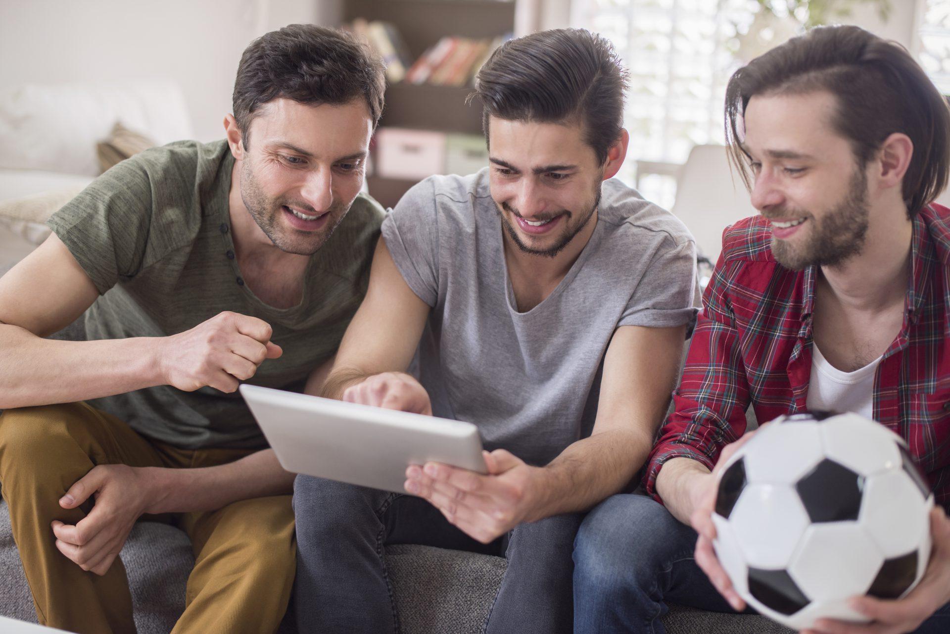 mężczyźni oglądają mecz piłki nożnej na tablecie