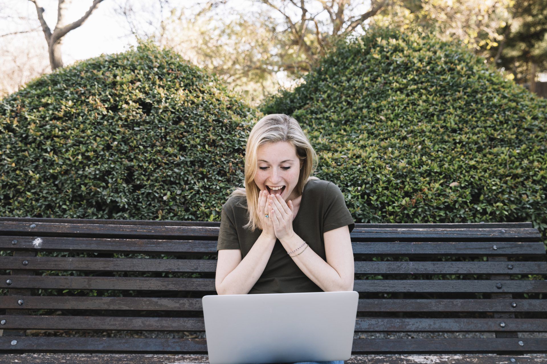 surprised woman using laptop bench