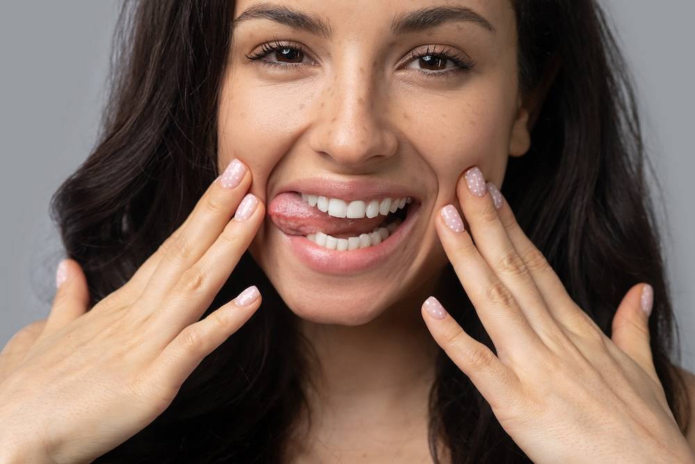 Beautiful dark haired girl doing face yoga and smiling