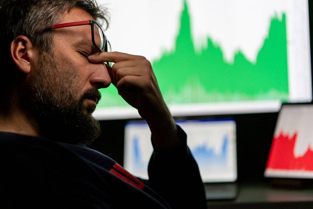 Depressed businessman in front of computer with graph of unsuccessful business on the screen