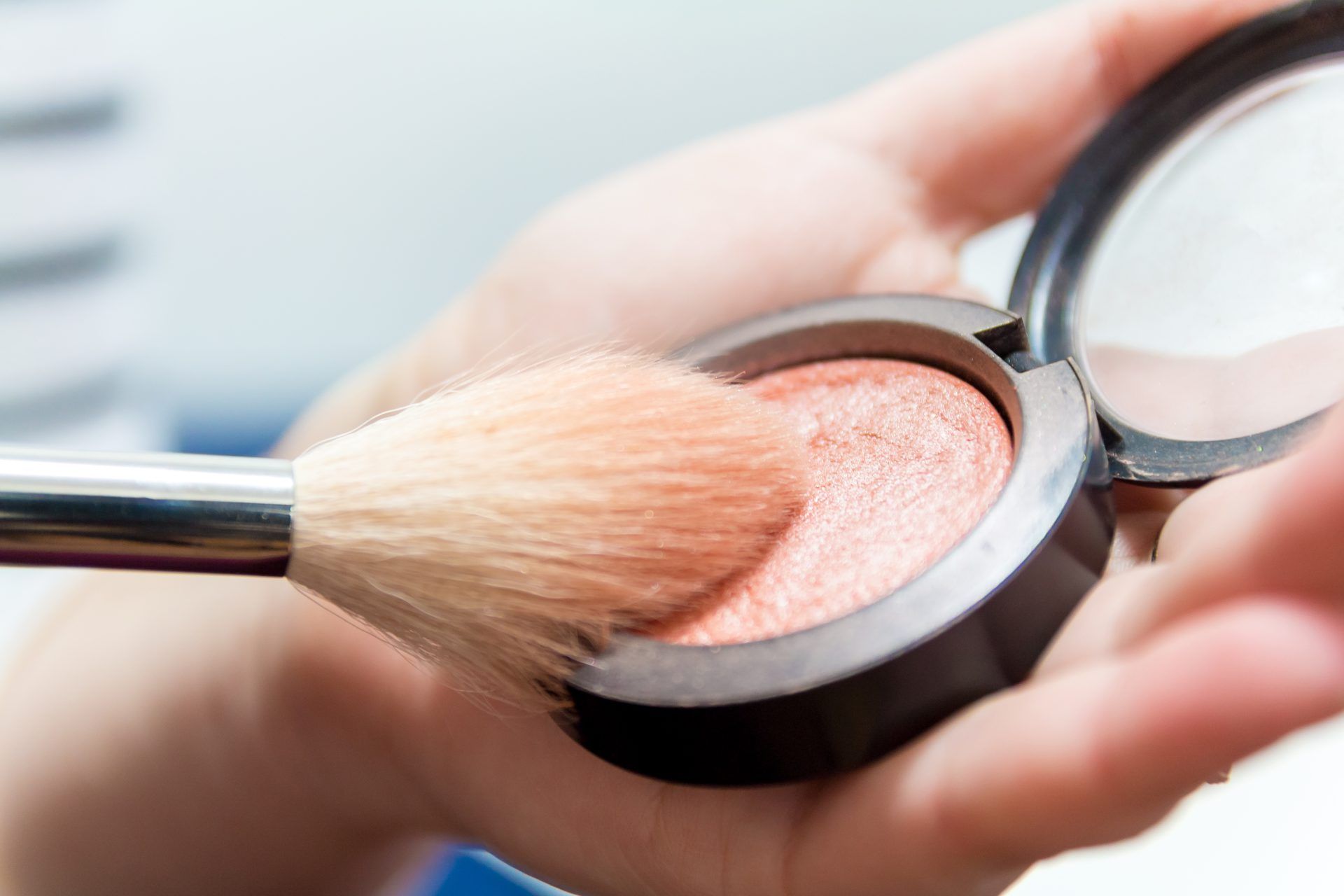 cropped woman hands applying face powder