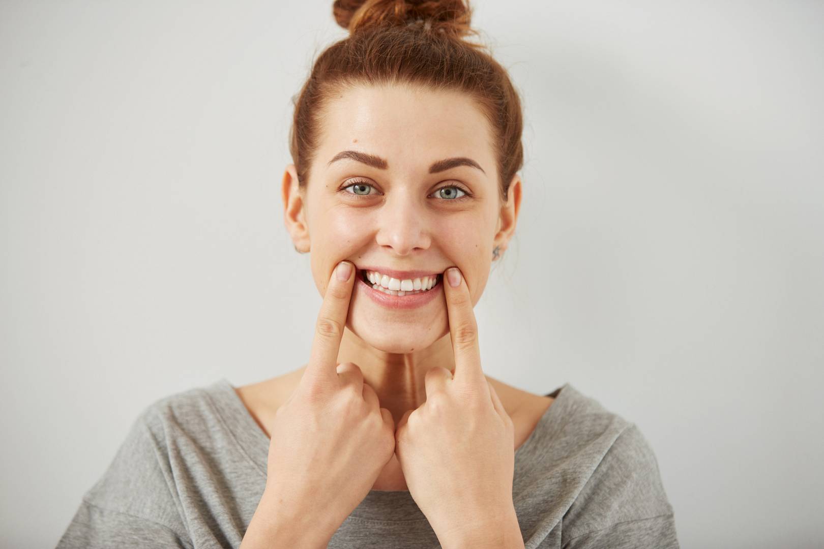 Funny woman on grey background. Cheerful female model joyful. Positive human emotion facial expression body language.