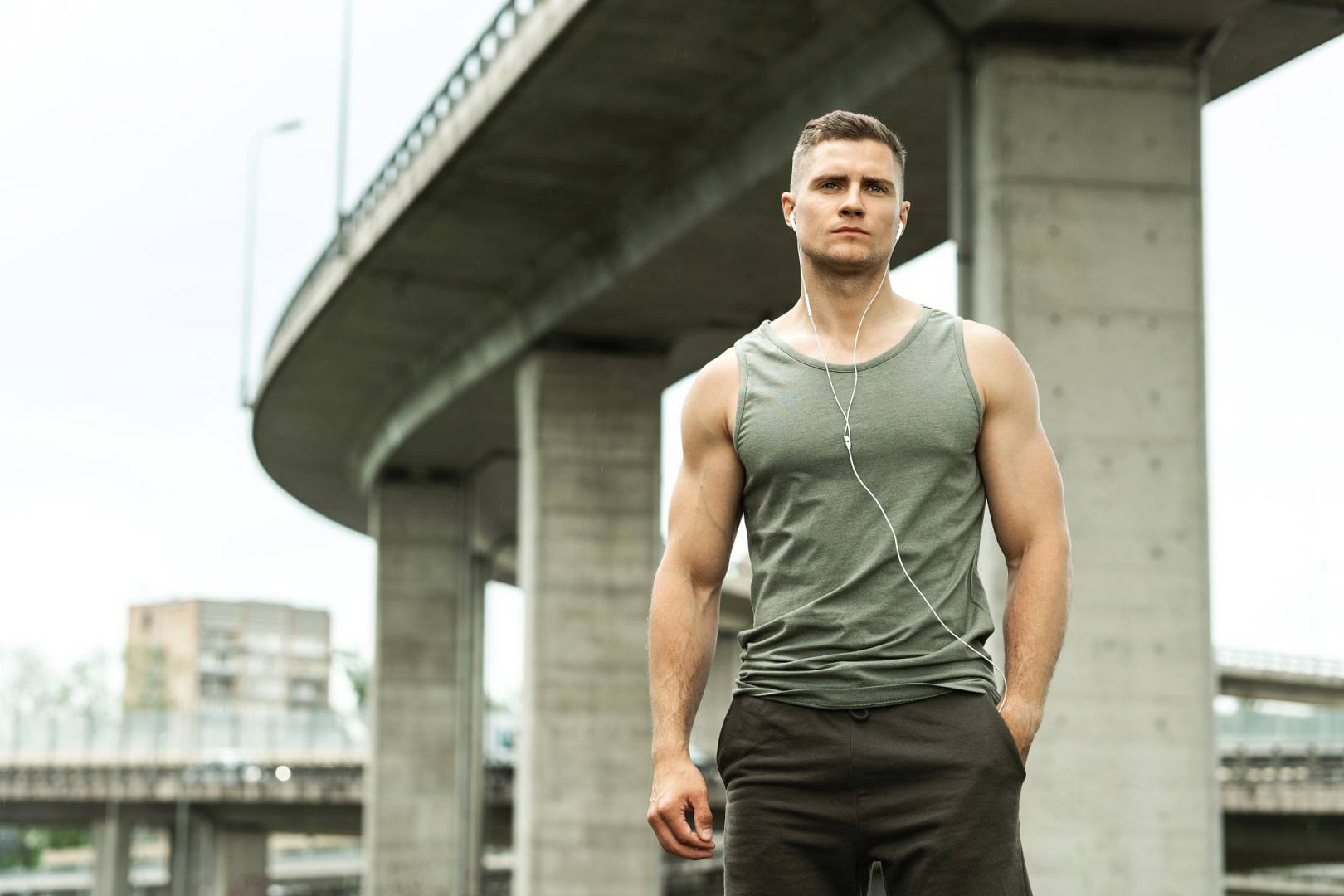 Handsome man with an earphones. Listening music during a fitness workout on a street.