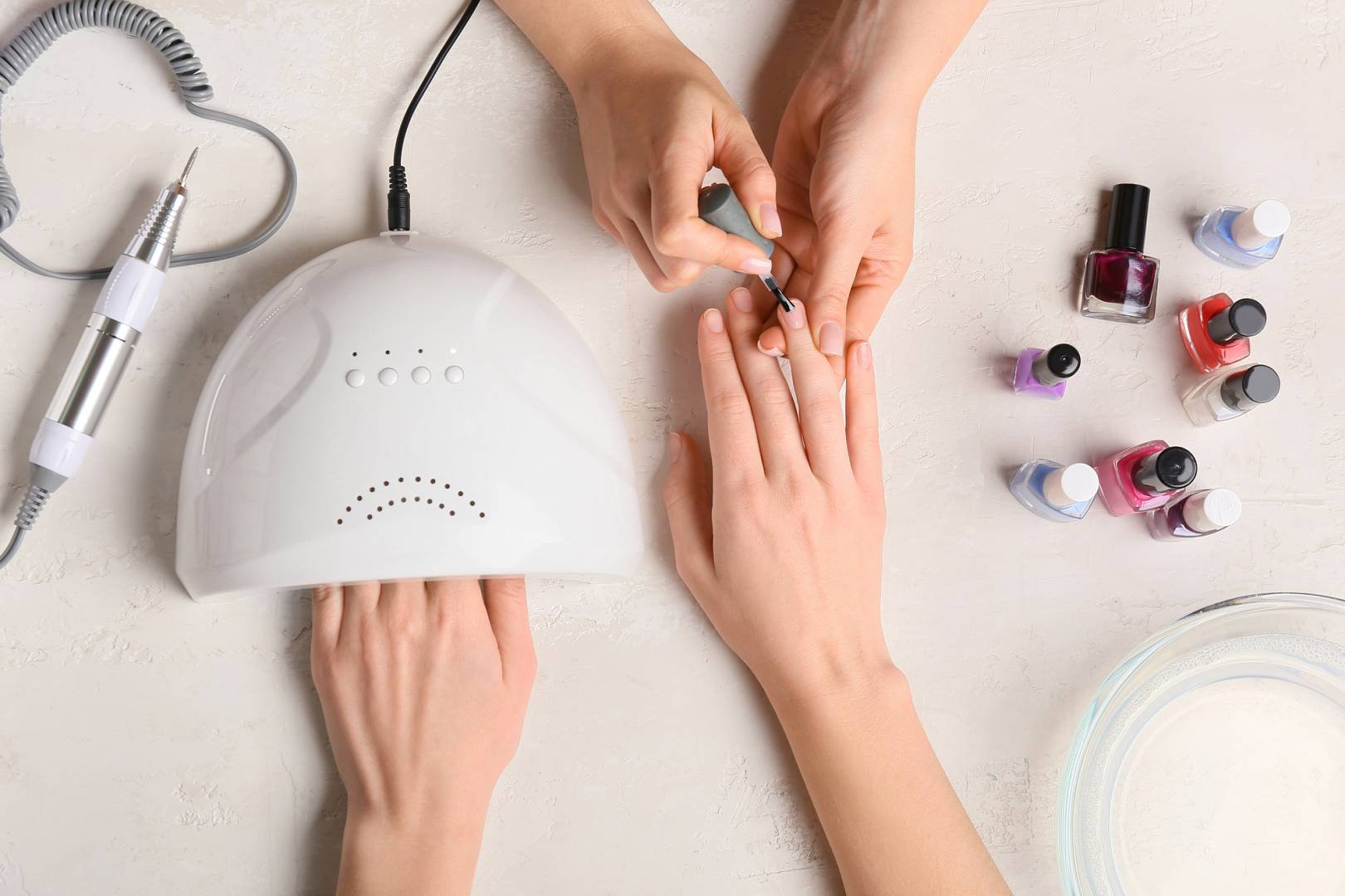 Manicure master applying nail polish on light table