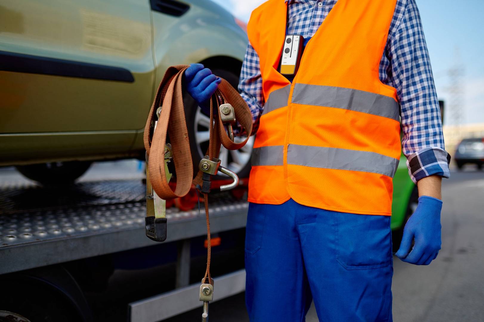 Male tow truck assistant holding fastening belts