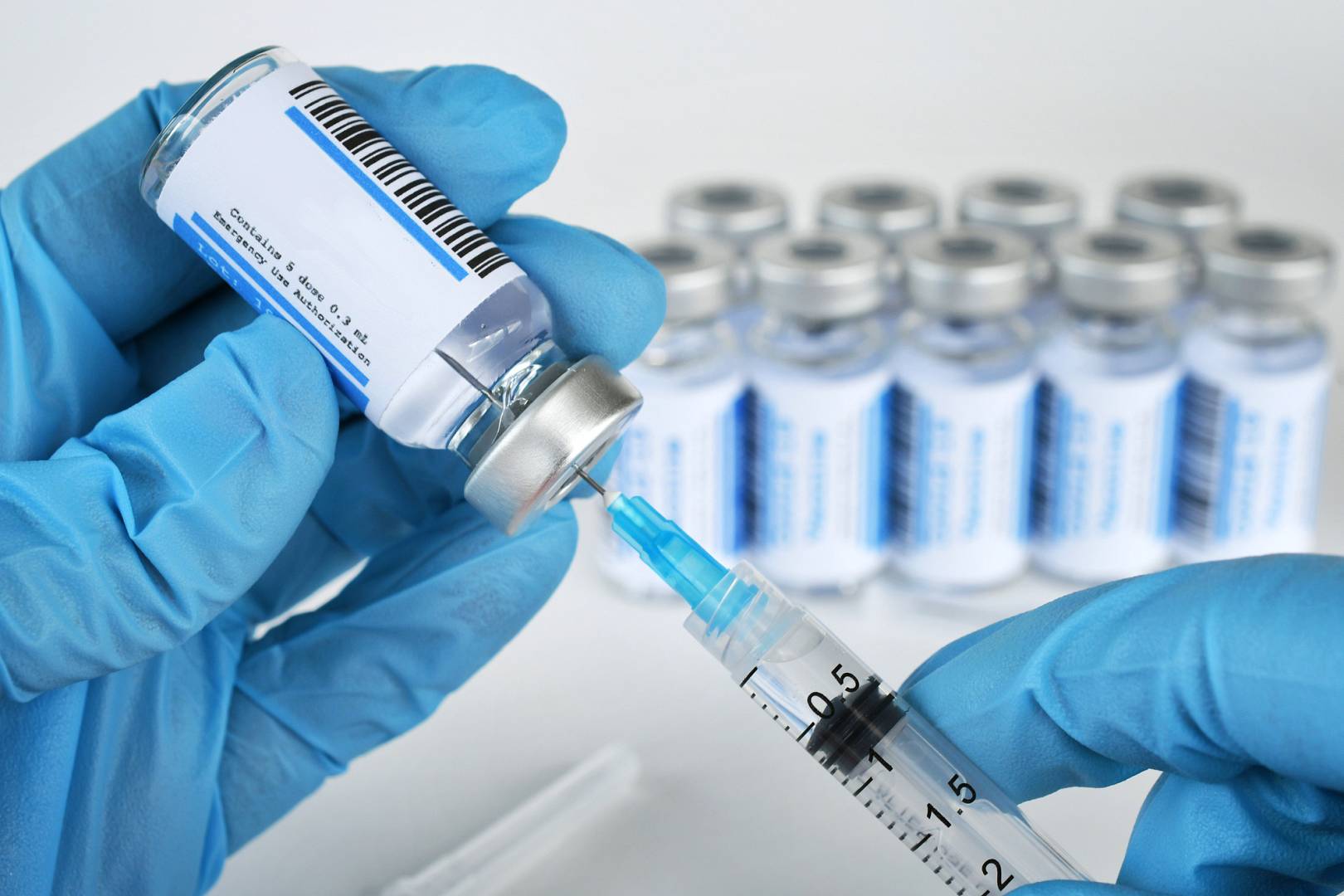 Medical personnel filling a syringe needle with generic vaccine