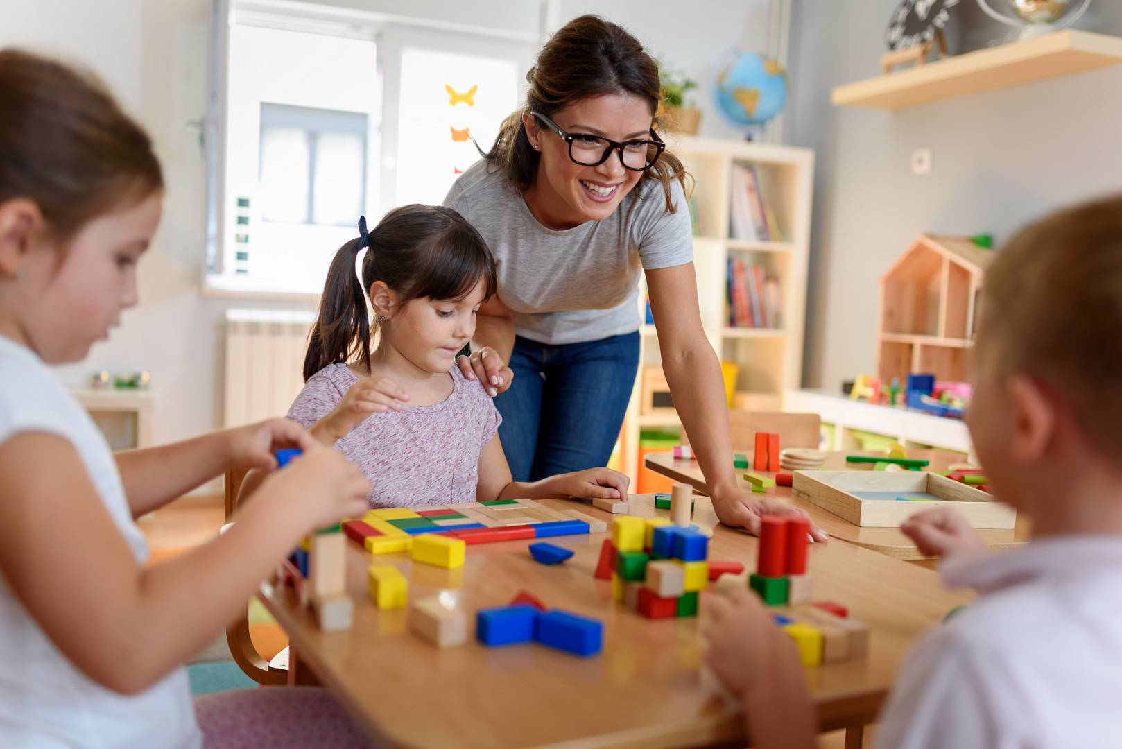 Preschool teacher with children playing with colorful wooden did