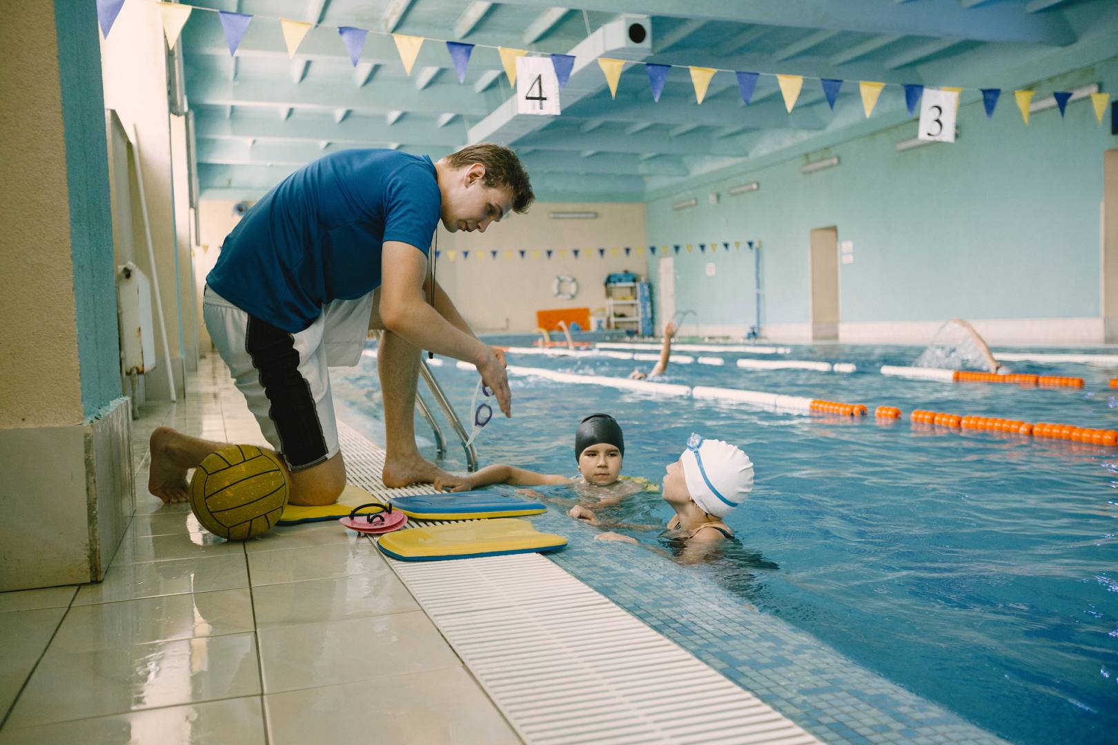 Male instructor teaches children how to swim