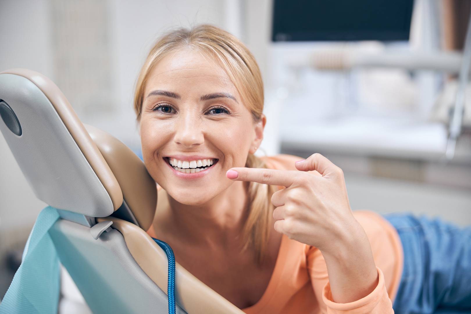 Merry young woman demonstrating perfect smile in clinic