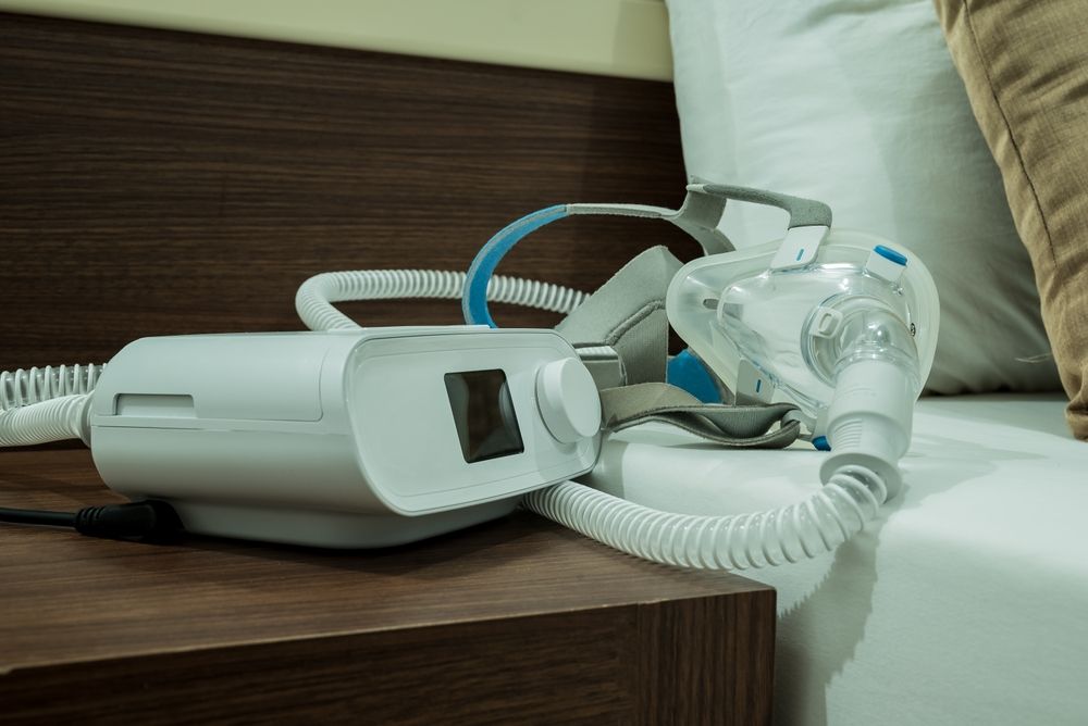 Aparat CPAP położony na szafce nocnej przy łóżku